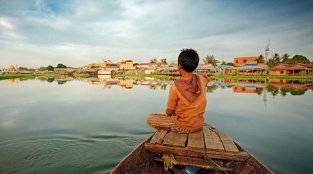 A young Cambodian boy on a boat approaching a floating village on the Tonle Sap in Siem Reap, Cambodia.