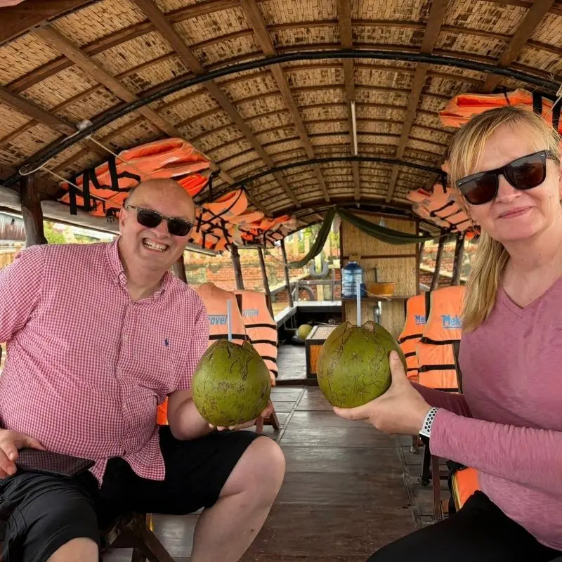Happy travelers enjoying fresh coconuts during a Vietnam vacation with VietVision